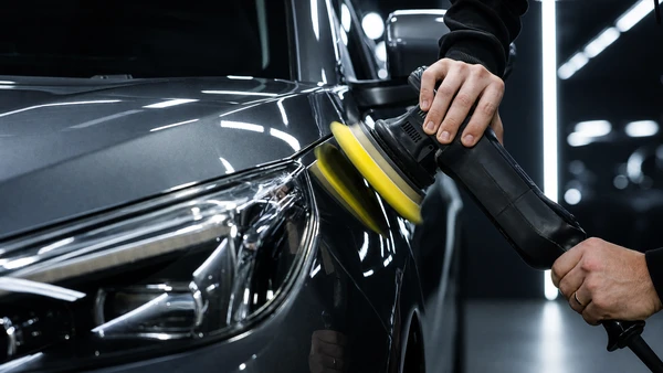 Mécanicien automobile en combinaison bleue remplace une batterie dans le compartiment moteur d'un véhicule